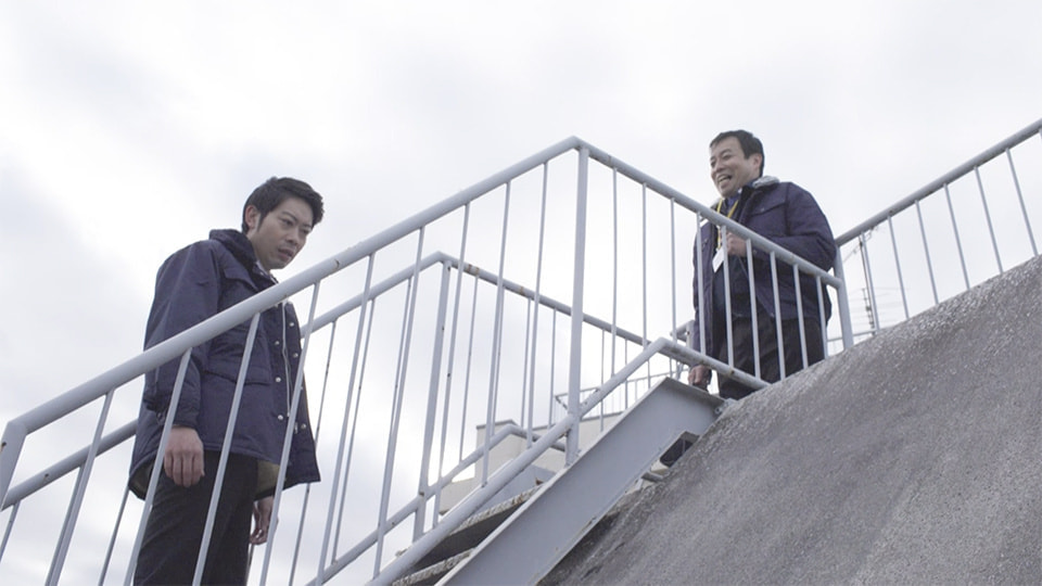 屋上で密談する男性